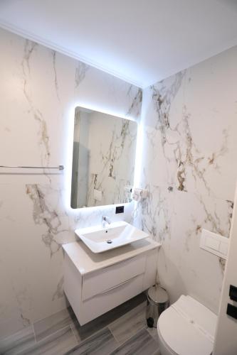 Un baño blanco con lavabo y espejo. en Dallga Suites, en Tushemisht