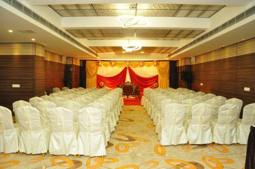 a room with white chairs and a red curtain at Hotel Atrium in Erode