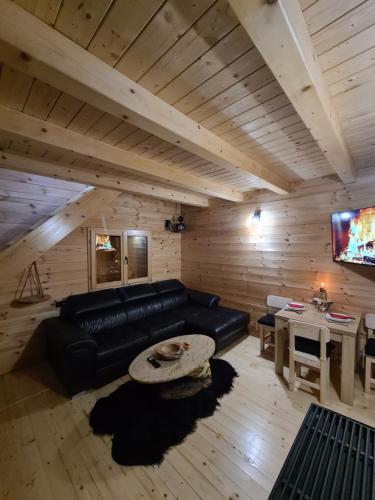 a living room with a black leather couch and a tv at Apartment Homeland in Kolašin