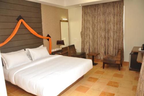 a bedroom with a large white bed with an orange headboard at Hotel Atrium in Erode