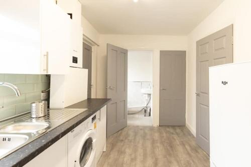 a white kitchen with a sink and a washing machine at Origin - Close 2 city-centre, Shops, Netflix in Kirkstall