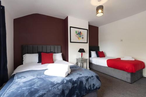 1 dormitorio con 2 camas y almohadas rojas en Origin - Close 2 city-centre, Shops, Netflix, en Kirkstall