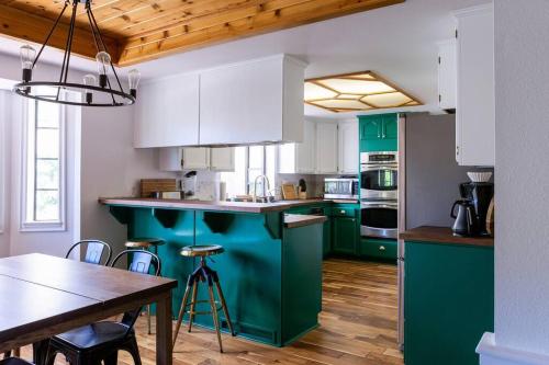 una cocina con armarios verdes y blancos y una mesa en Apres-Ski Chalet Mt High Wrightwood Ski Resort en Wrightwood