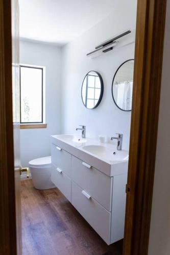 a bathroom with a sink and a toilet and mirrors at Apres-Ski Chalet Mt High Wrightwood Ski Resort in Wrightwood