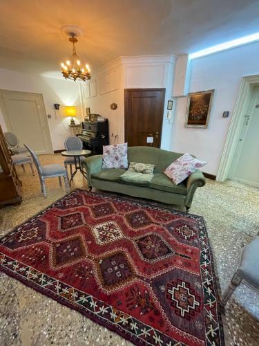 Lions Venice Guest house في البندقية: غرفة معيشة مع أريكة خضراء وسجادة حمراء