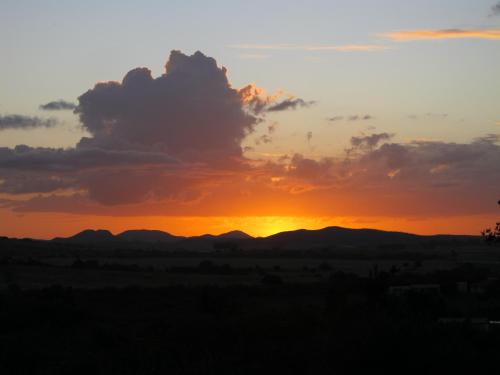 a sunset over a field with mountains in the background at Cabaña Los Pololos in Villa Serrana