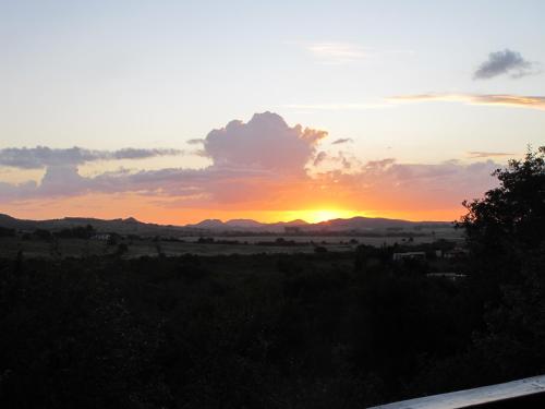 a sunset over a field with mountains in the background at Cabaña Los Pololos in Villa Serrana