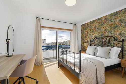 a bedroom with a bed and a desk and a window at WHome Surfer's Paradise Retreat: Digital Nomads & Remote Workers in Ericeira