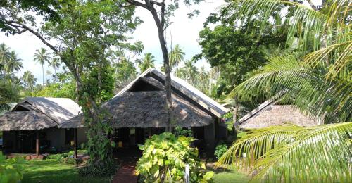 una casa con techo de paja en un bosque en Entire Beach Front Resort Home - Tides Reach Beach House en Saraotou