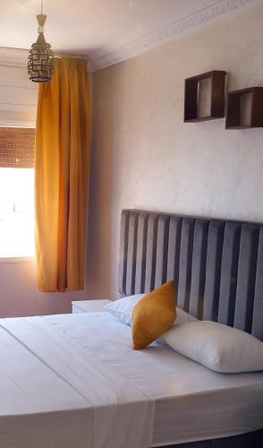 a bedroom with a bed with a yellow pillow on it at Luxury Apartement in City Center F2 in Tangier