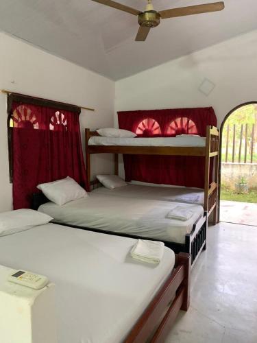 1 dormitorio con 2 literas y cortinas rojas en EL RANCHO DE NUMA en Arboletes
