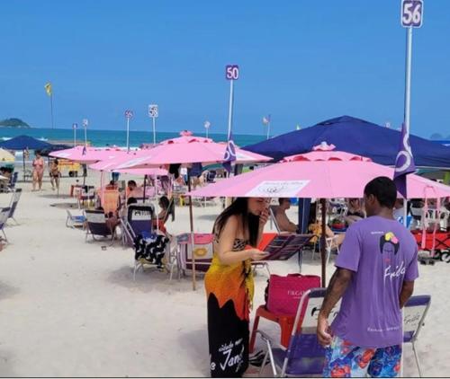 a man and a woman standing under an umbrella on the beach at Hotel Rosa da Ilha Guaruja - Perto do Mar com piscina in Guarujá