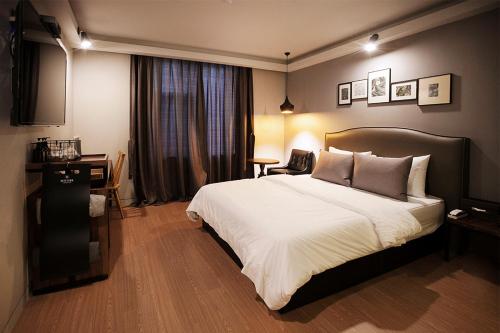 a bedroom with a large white bed and a desk at Brown Dot Hotel GimhaeEobang in Gimhae