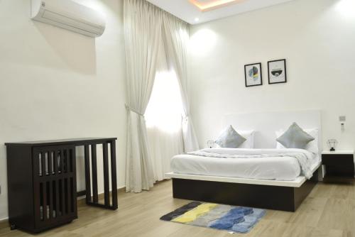 a white bedroom with a bed and a window at ABODE APARTMENTS in Lagos