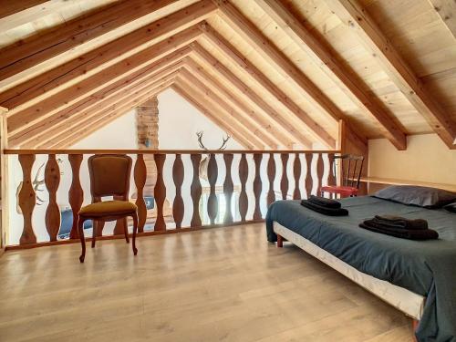 um quarto com uma cama e uma cadeira num sótão em Gîte authentique -Mont Lozère em Les Bondons