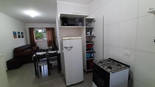 a small kitchen with a stove and a refrigerator at AP Bertioga - Praia Indaia - Wi-Fi 500 Mega in Bertioga