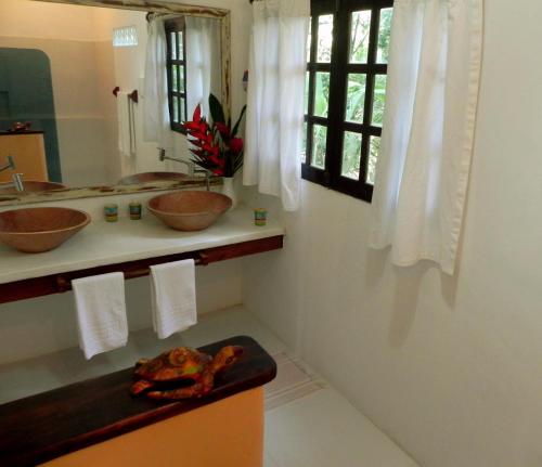 uma casa de banho com 2 lavatórios e um espelho em Calypso INN em Trancoso