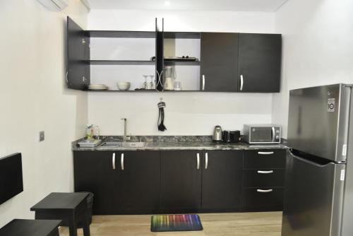 a kitchen with black cabinets and a stainless steel refrigerator at ABODE APARTMENTS in Lagos