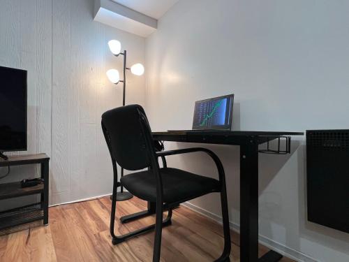 uma secretária com um computador portátil e uma cadeira num quarto em Bertha's charming urban retreat em Laval