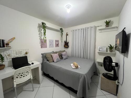 a bedroom with a bed and a desk with a laptop at Quarto Encantado in João Pessoa