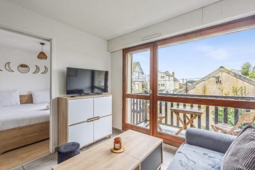 un salon avec un lit et une grande fenêtre dans l'établissement Appartement Alfredo - Welkeys, à Cabourg