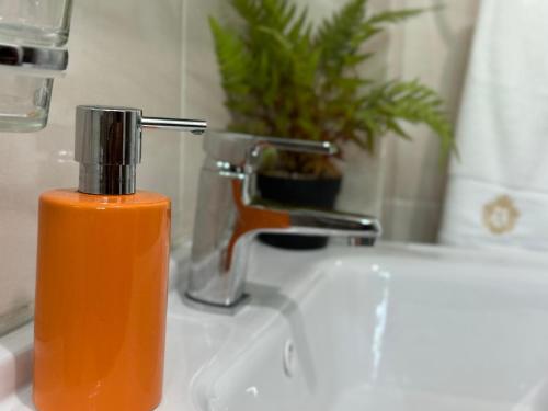 a bottle of orange soap sitting on a bathroom sink at Moderno Penthouse in Solorín