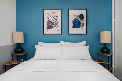 une chambre bleue avec un lit blanc et trois photos sur le mur dans l'établissement Balyam Suites Montorgueil - Sentier, à Paris