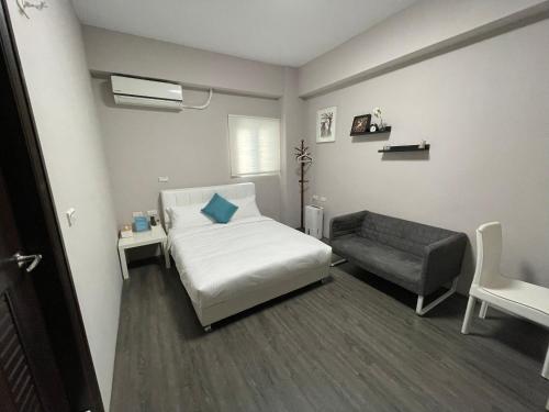 1 dormitorio pequeño con 1 cama y 1 silla en SummerMallika 夏茉民宿, en Magong