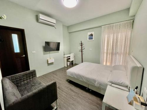 ein Schlafzimmer mit einem Bett, einem Stuhl und einem TV in der Unterkunft SummerMallika 夏茉民宿 in Magong