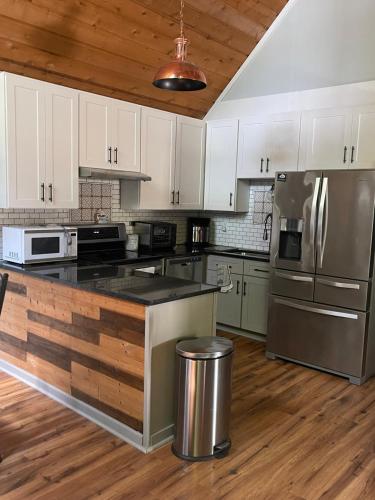 a kitchen with white cabinets and a stainless steel refrigerator at Heaven on Lake Sinclair in Resseaus Crossroads