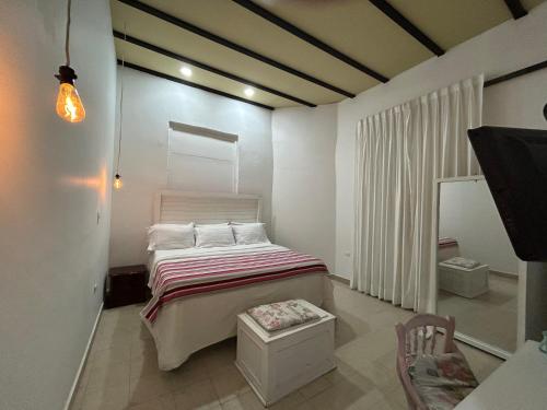 a small bedroom with a bed and a chair at Hotel La Casa Ovalle in San Vicente de Chucurí