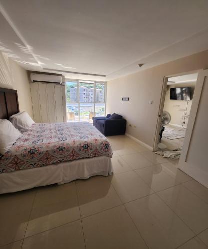um quarto com uma cama e uma grande janela em Balcony Sea Breeze @ Bayfront Villas Portmore em Portmore