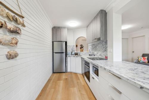 a kitchen with white walls and a stainless steel refrigerator at Sea Tonic on Market in Woolgoolga