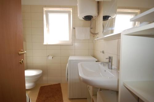 a bathroom with a sink and a toilet and a window at Apartments with parking space Porat, Krk - 22268 in Porat