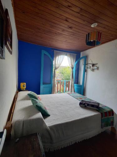- une chambre avec un grand lit et un mur bleu dans l'établissement Onda Verde Hostal, à Reyes