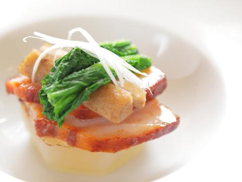 a piece of food with cheese and greens on a plate at 水と緑のやすらぎの宿　一の瀬 in Mishima