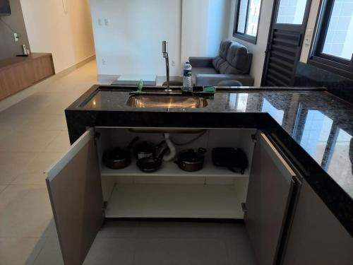 a kitchen with a sink and a living room at Espaço aconchegante com wifi! in Patos de Minas