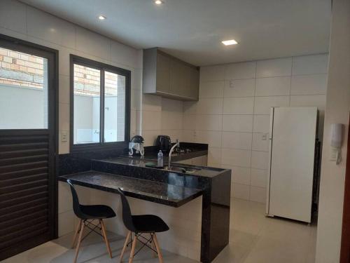 a kitchen with a counter with two chairs and a refrigerator at Espaço aconchegante com wifi! in Patos de Minas