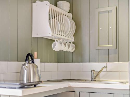 una cocina con platos blancos en un estante y un fregadero en 1 Bed in Totnes 93063 en Marldon