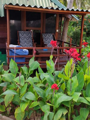 a porch with two chairs and some red flowers at Bella Nilaveli Beach in Nilaveli