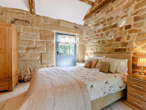 a bedroom with a bed in a stone wall at 2 Bed in Helmsley 93098 in Chop Gate