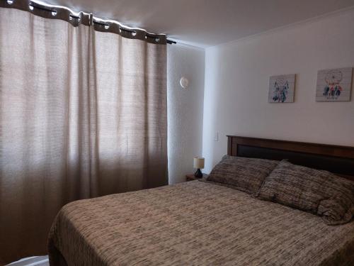 1 dormitorio con 1 cama y una ventana con cortinas en Departamento Ciudad de Caldera, Bahia Inglesa, en Caldera