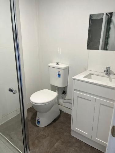 een witte badkamer met een toilet en een wastafel bij Master Bedroom opposite to Deakin University in Burwood