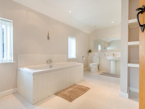 a white bathroom with a tub and a toilet at 5 Bed in Brecon 90660 in Lower Chapel