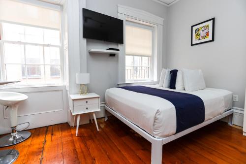 ein weißes Schlafzimmer mit einem großen Bett und zwei Fenstern in der Unterkunft Charming & Stylish Studio on Beacon Hill #12 in Boston