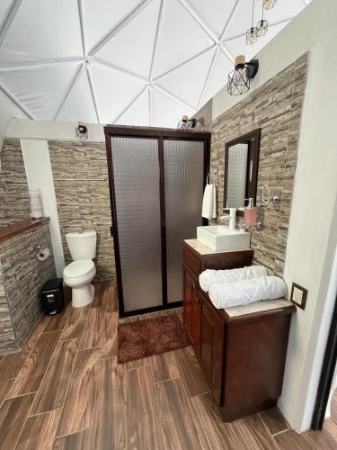 a bathroom with a sink and a toilet and a mirror at El Gato Glamping con vista al valle in Huasca de Ocampo
