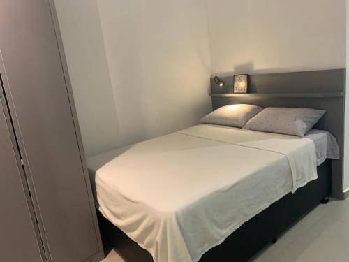 a small bedroom with a bed with a white bedspread at Studio Metrô Brooklin in Sao Paulo