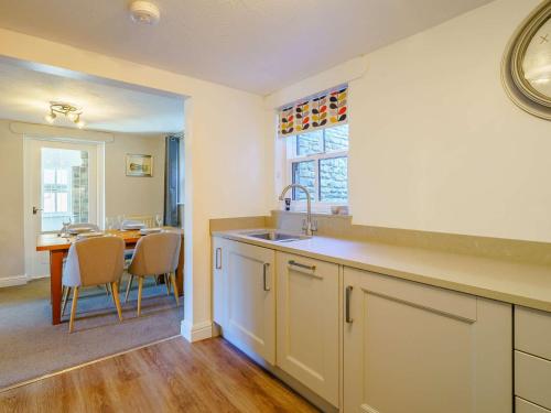 a kitchen with a sink and a dining room with a table at 2 Bed in Sedbergh 89266 in Milnthorpe