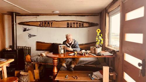 Un uomo seduto a un tavolo in una stanza del treno di Refugio Jemmy Button a Puerto Williams