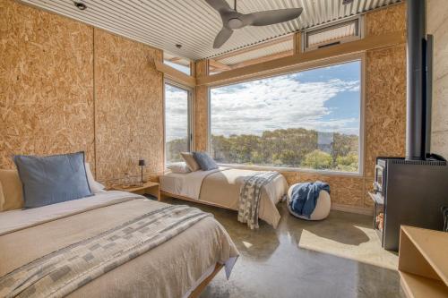 two beds in a room with a large window at Immerse Kangaroo Island in D'Estrees Bay